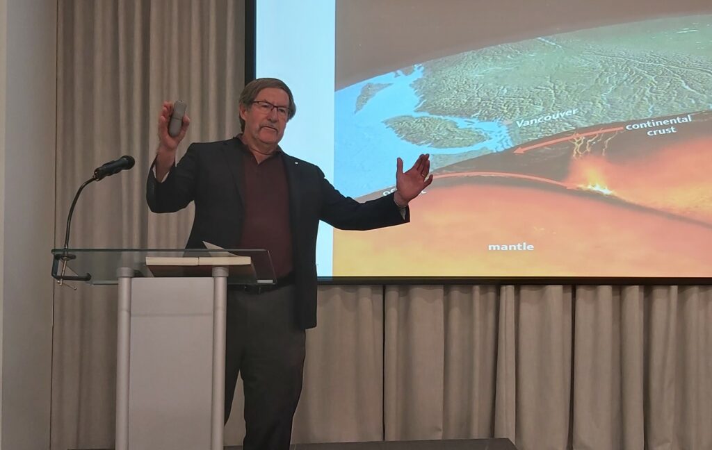 Dr. John Clague at the podium, with a slide behind him that depicts the continental crust and earth's mantle in the area of Vancouver.