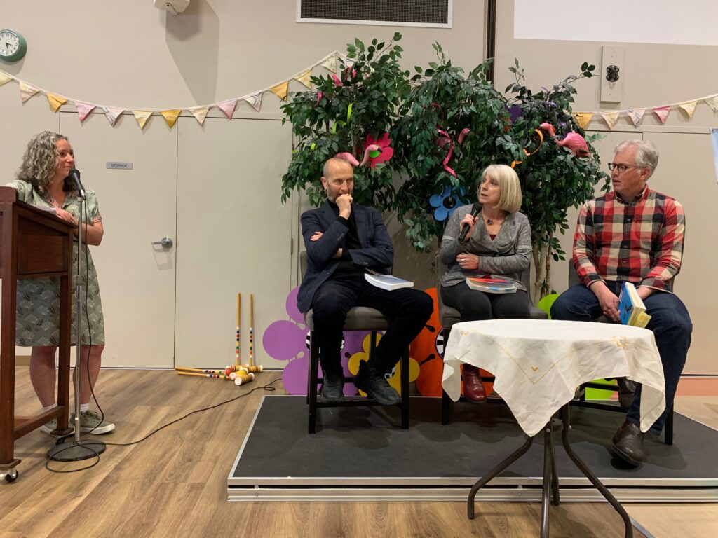 Front of the room at the Sidney LitFest tea, with moderator Deborah Rogers (far left) at the podium and seated on a riser, left to right, authors CC Humphreys, Frances Peck (speaking into the mic) and Gregor Craigie